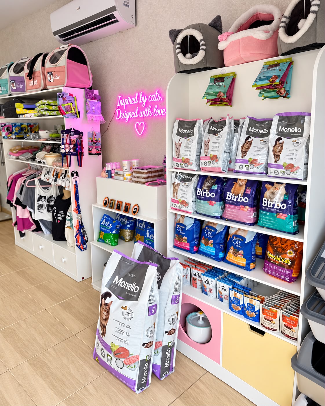 Astoria Cats Boutique in Paraguay: bright interior with white shelves of cat food, plush cat beds, bowls, toys and collars, and a pink neon sign reading 'Inspired by cats, Designed with love'